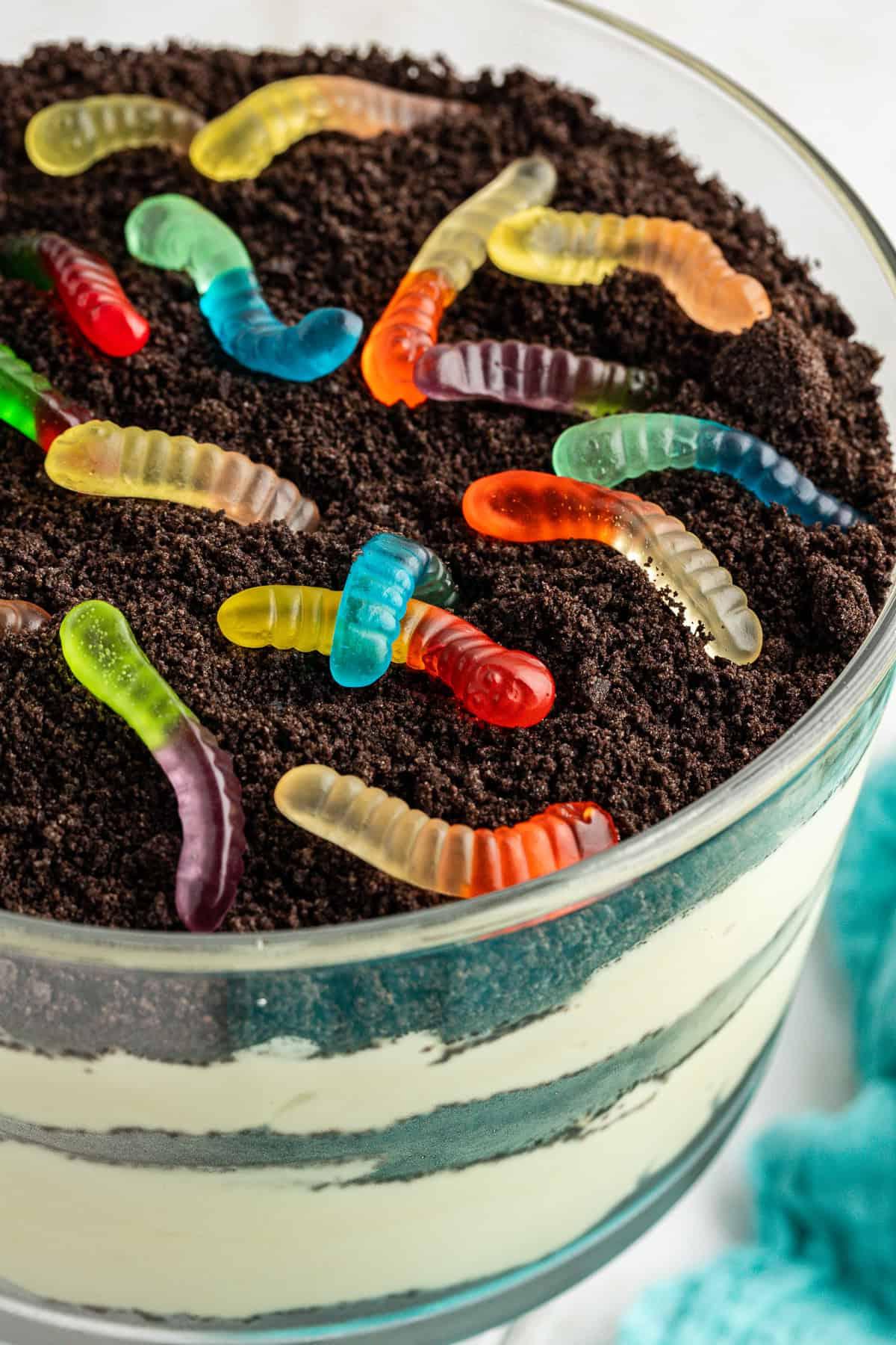 La migliore ricetta per la Torta al Fango 2 Primo piano di una grande ciotola da trifle di torta di terra guarnita con Oreo sbriciolati e vermi gommosi