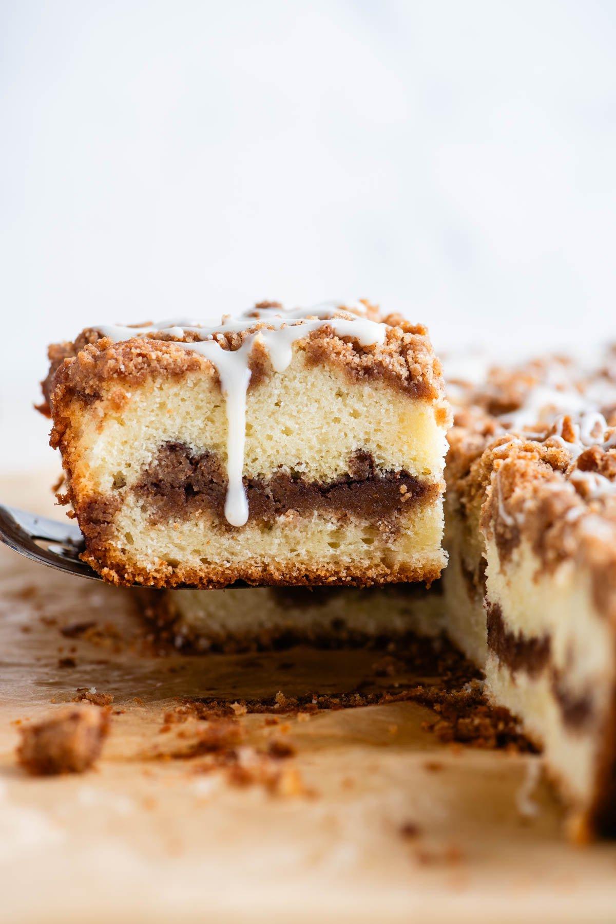 Ricetta Torta Umida al Caffè 2 Una fetta di torta al caffè con glassa che cola sul lato, sollevata da una spatola dal resto della torta