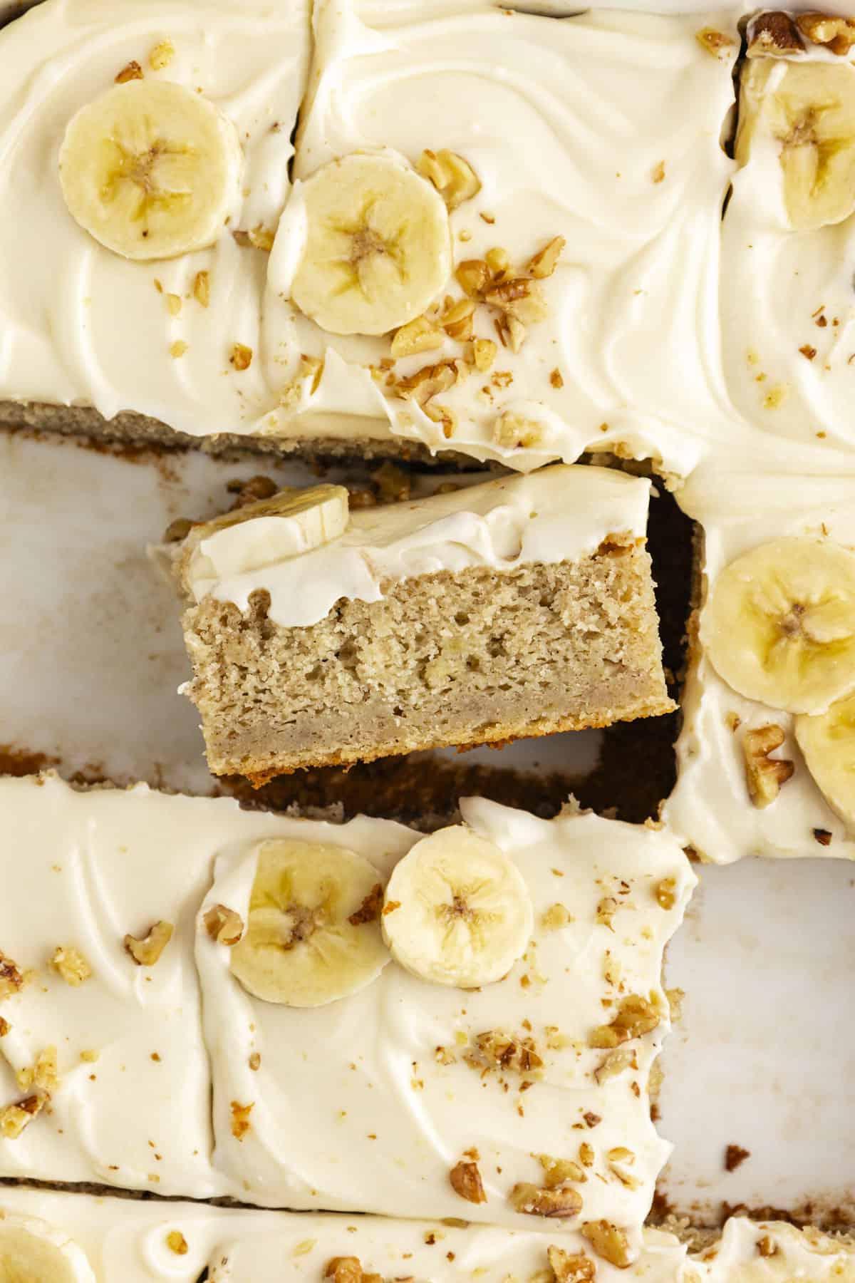 Ricetta Facile Torta alla Banana 2 Una fetta ravvicinata di torta di banane con alcune fette mancanti e una fetta girata su un lato in modo da poter vedere lo strato di torta e lo strato di glassa sopra
