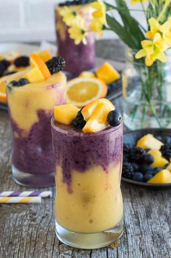 Questo smoothie hawaiano ai frutti di bosco a due strati presenta uno strato arancione al mango e uno strato ai frutti di bosco! Guarnisci lo smoothie con uno spiedino di frutta fresca!
