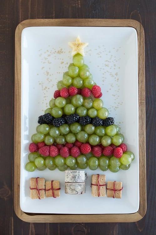 Albero di Natale di Frutta 2 Piatto di frutta a forma di albero di Natale con uva verde, lamponi e more su un vassoio bianco