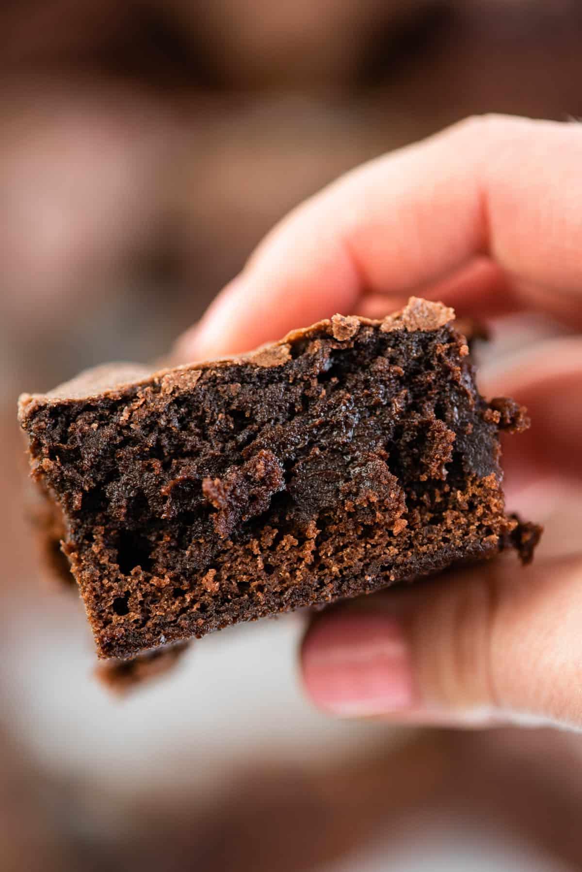 Mano che tiene una fetta di brownie fudgy