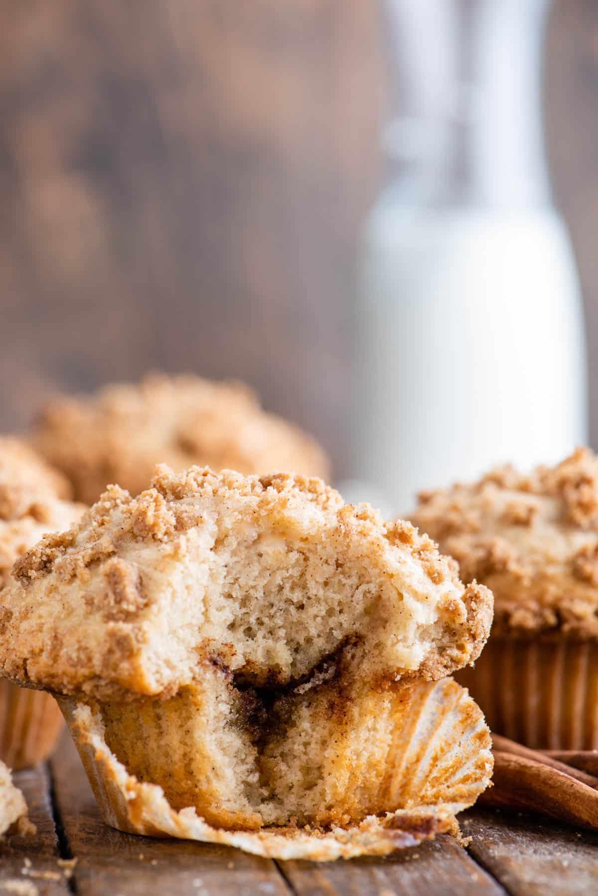 Muffin alla Sbriciolata 2 muffin al caffè con un morso che mostra lo strato di cannella all'interno su sfondo di legno