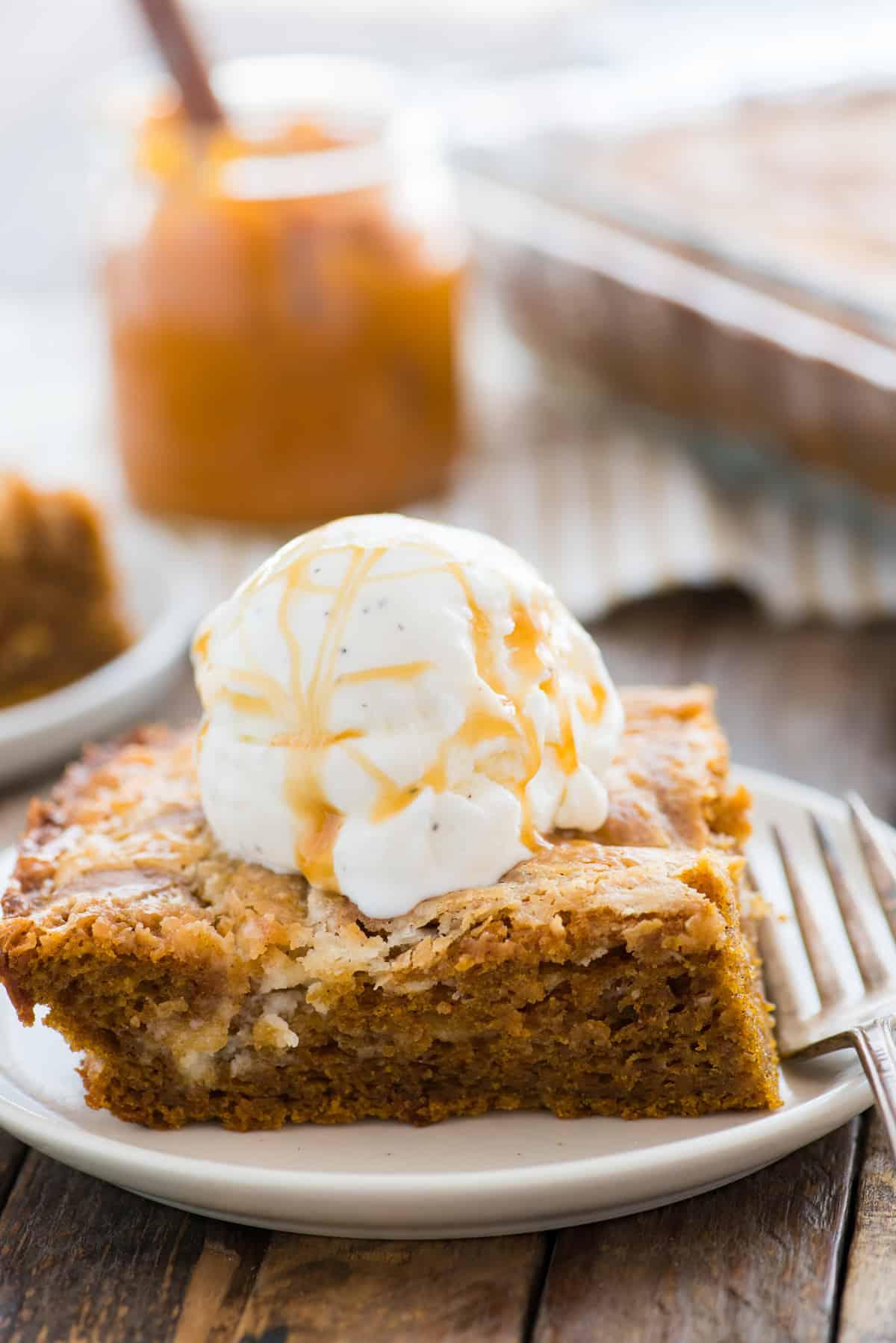 Fetta di torta terremoto alla zucca su piatto bianco con una pallina di gelato alla vaniglia sopra