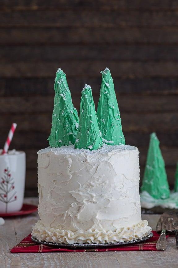 Squisita torta di pan di zenzero a tre strati con glassa alla vaniglia e decorazioni di alberi innevati, perfetta per le feste