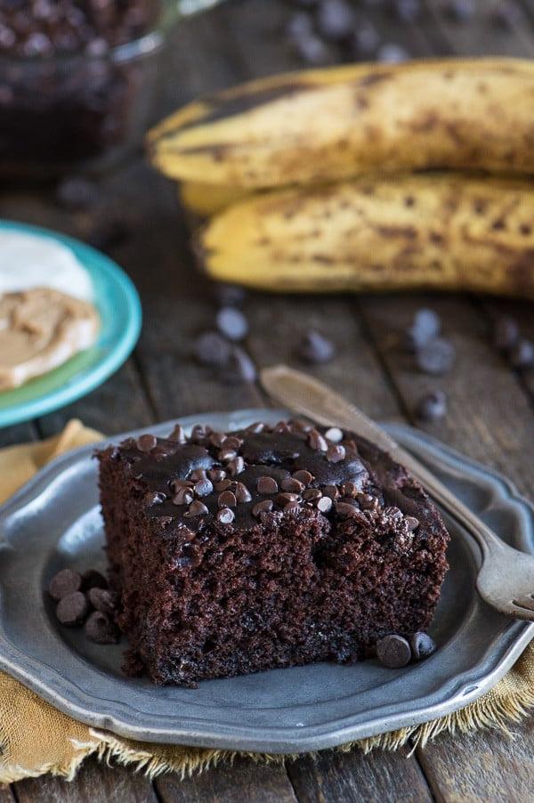 Torta al cioccolato più salutare 2 Fetta di torta al cioccolato salutare su piatto di metallo con banana sullo sfondo