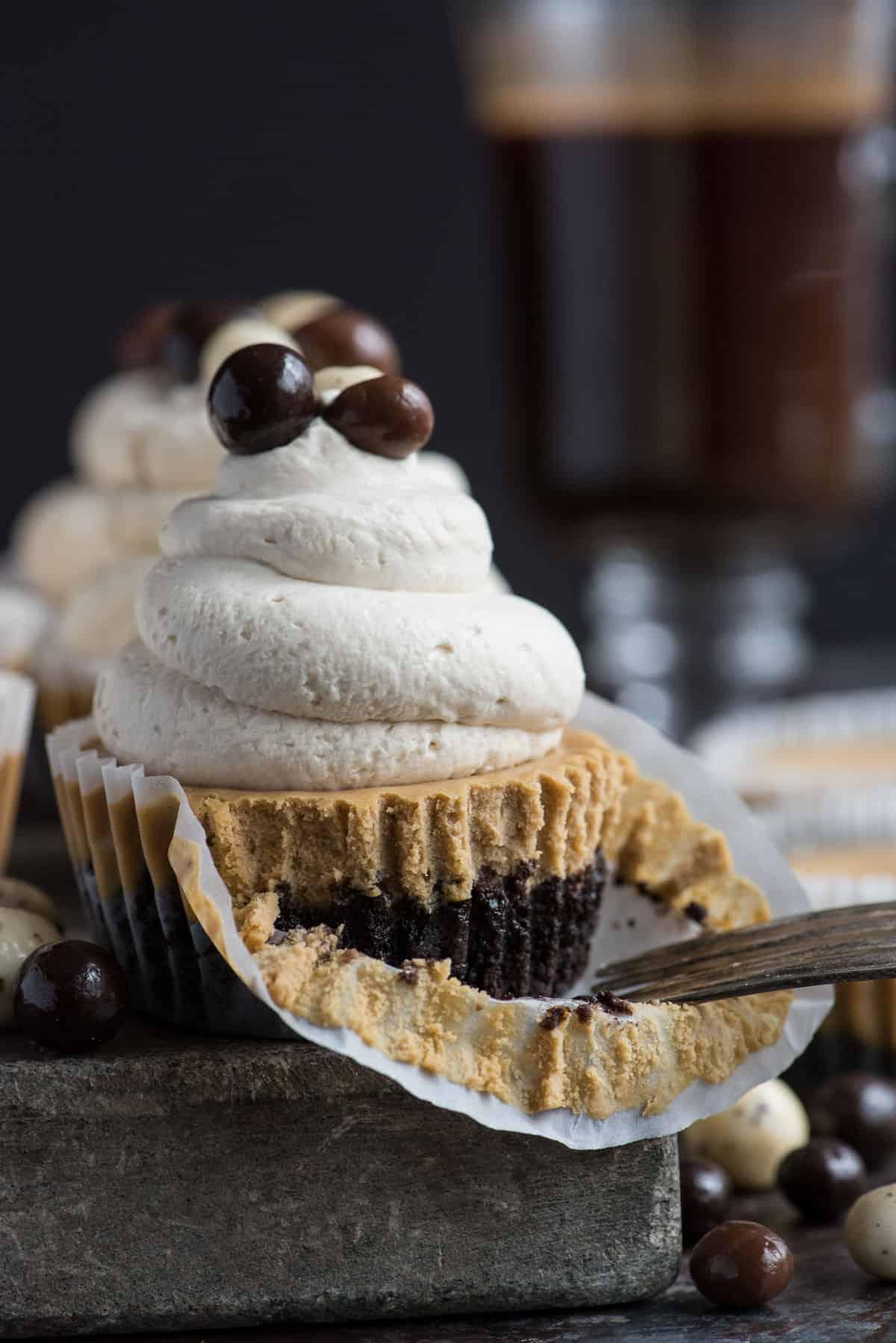 Questa è una ricetta di mini cheesecake al caffè che piacerà a tutti e che userai più e più volte! L'intera ricetta richiede solo 7 ingredienti e la prepari in uno stampo per muffin di dimensioni normali! Inoltre, puoi usare una base di Oreo o una base di cracker Graham per queste mini cheesecake all'espresso. #minicheesecake #coffeecheesecake #minicoffeecheesecake #espressocheesecake #mochacheesecake Mini cheesecake al caffè su lastra di pietra con panna montata e chicchi di caffè espresso