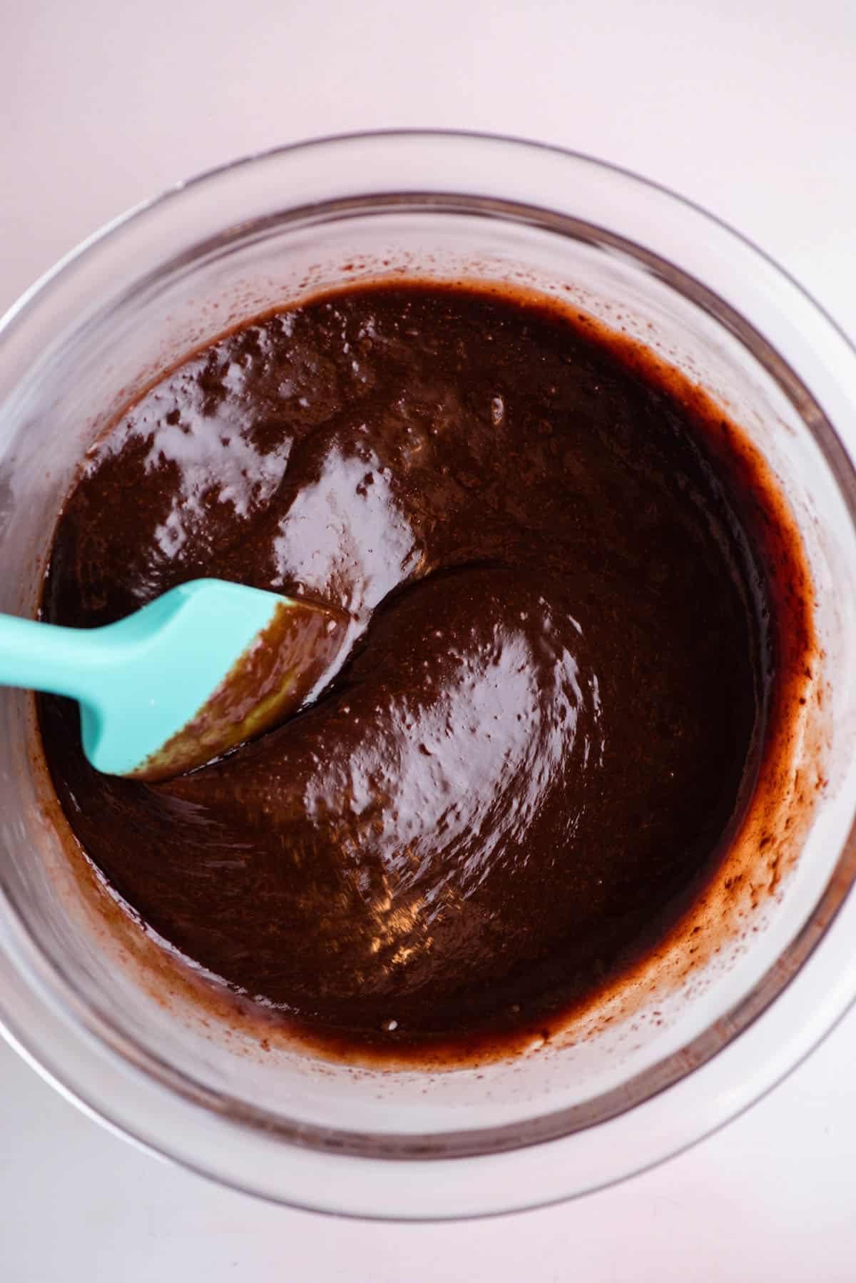 **Salsa Calda al Cioccolato Fondente** 11 Salsa hot fudge in una ciotola di vetro che è stata mescolata con una spatola color verde acqua appoggiata nella ciotola