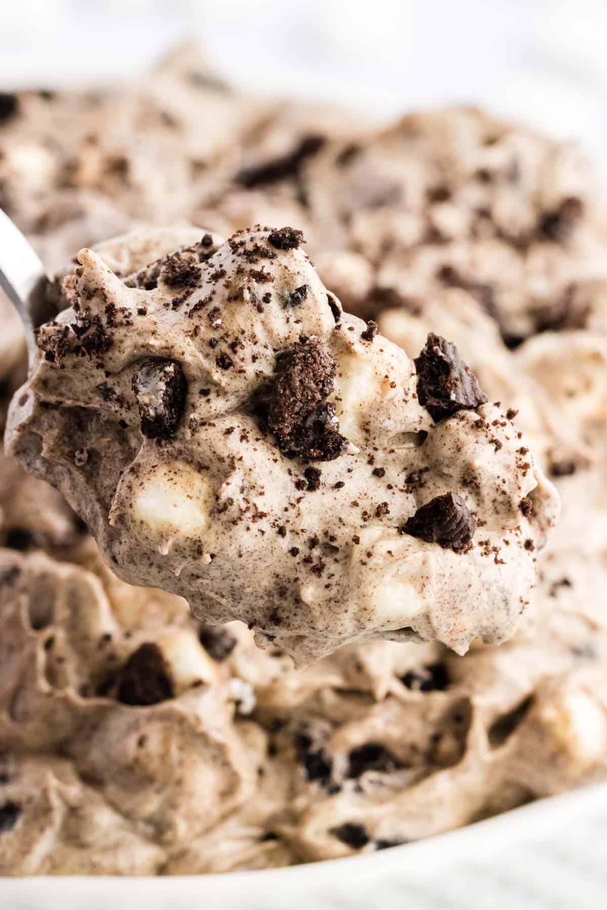 Ricetta Crema Soffice Oreo (Senza Formaggio Cremoso) 11 Primo piano di un cucchiaio pieno di fluff di Oreo sollevato da una ciotola piena di fluff di Oreo