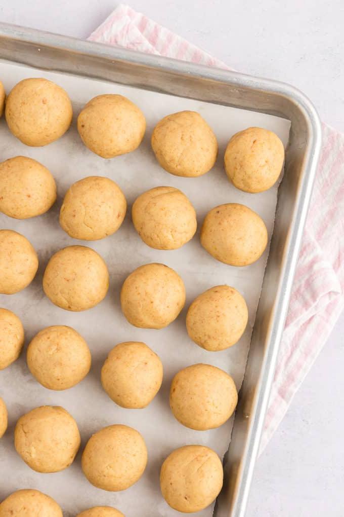una teglia rivestita con file di palline di cake pop, appoggiata su un asciugamano a strisce bianche e rosa