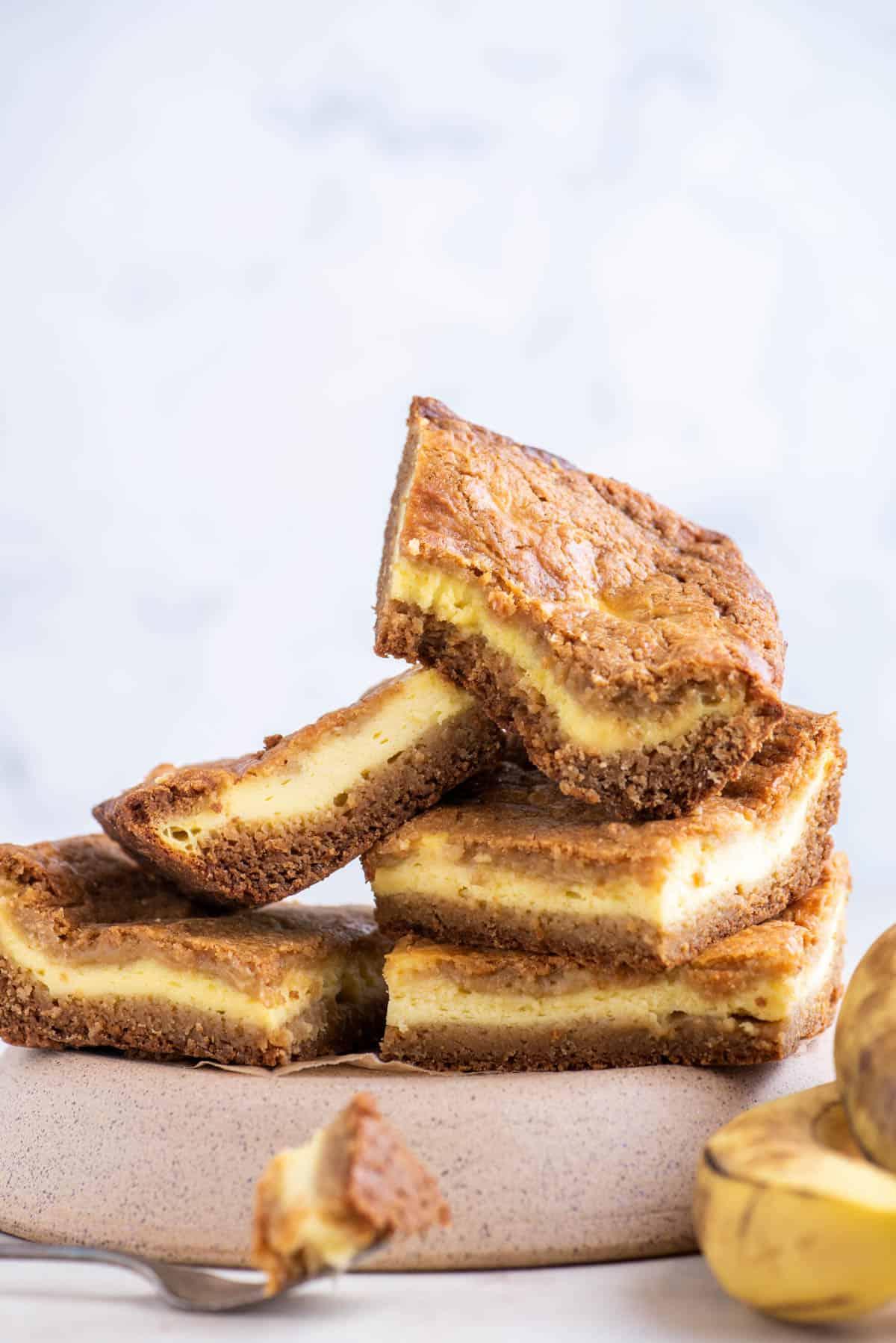 Brownies al Budino di Banana 11 5 blondies al budino di banana disposti in pila, con un morso in uno, che è su una forchetta davanti al piatto