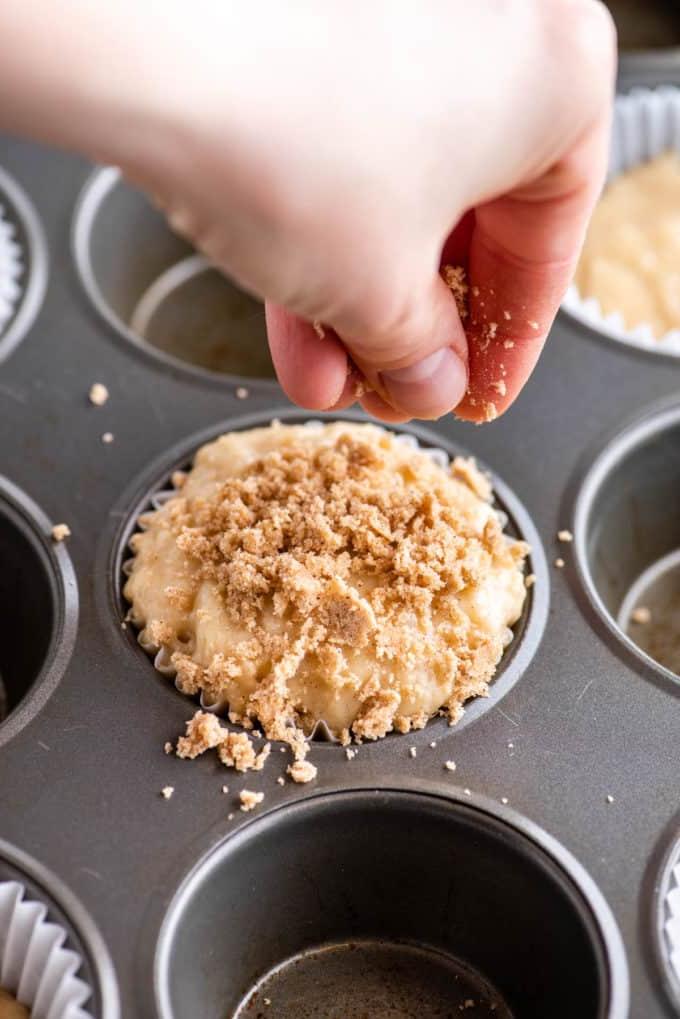 Muffin alla Sbriciolata 12 mano che aggiunge la copertura crumble al muffin