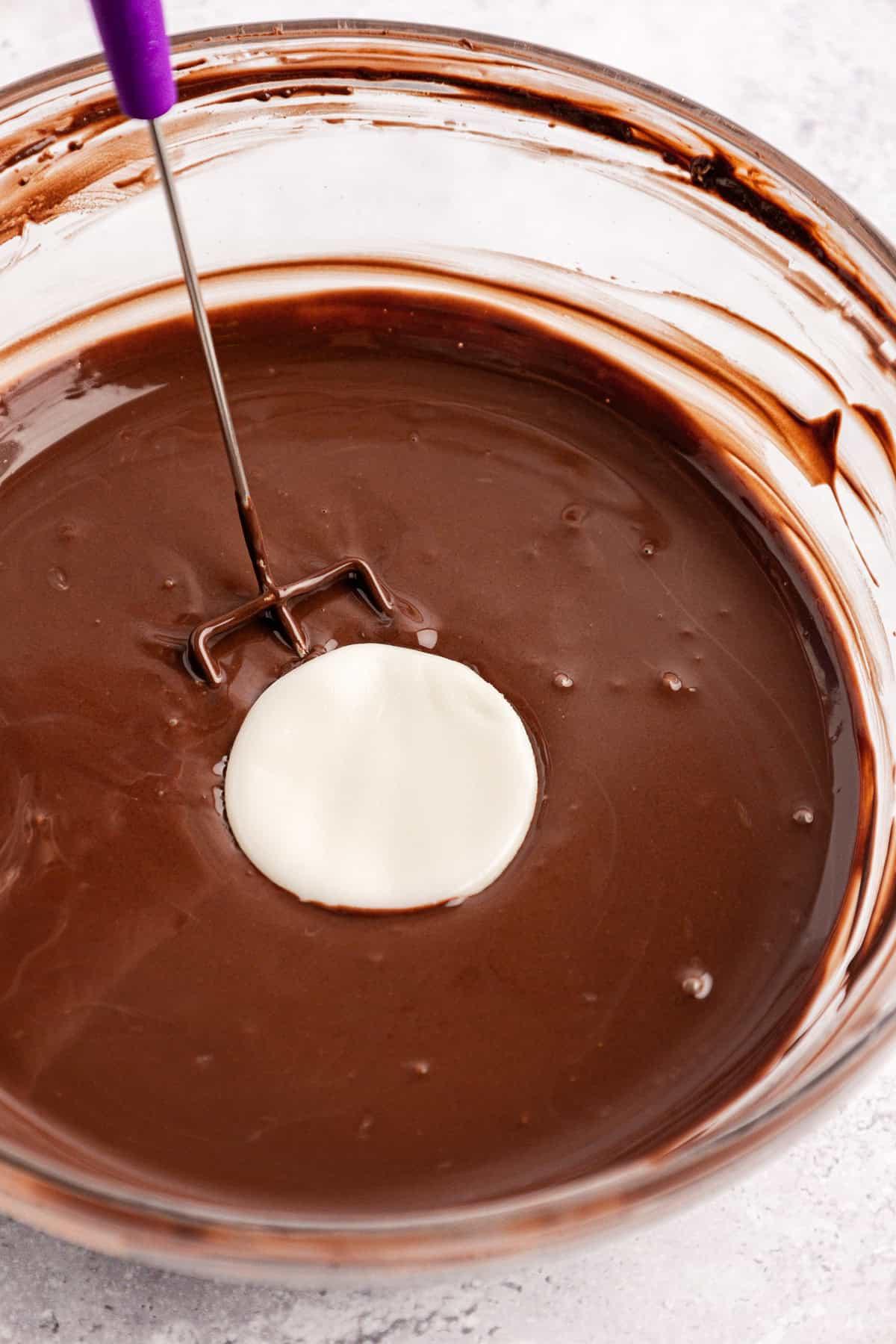Dischetti alla menta piperita York fatti in casa 12 Un disco bianco di ripieno di patty alla menta immerso in una ciotola di vetro trasparente piena di cioccolato fuso