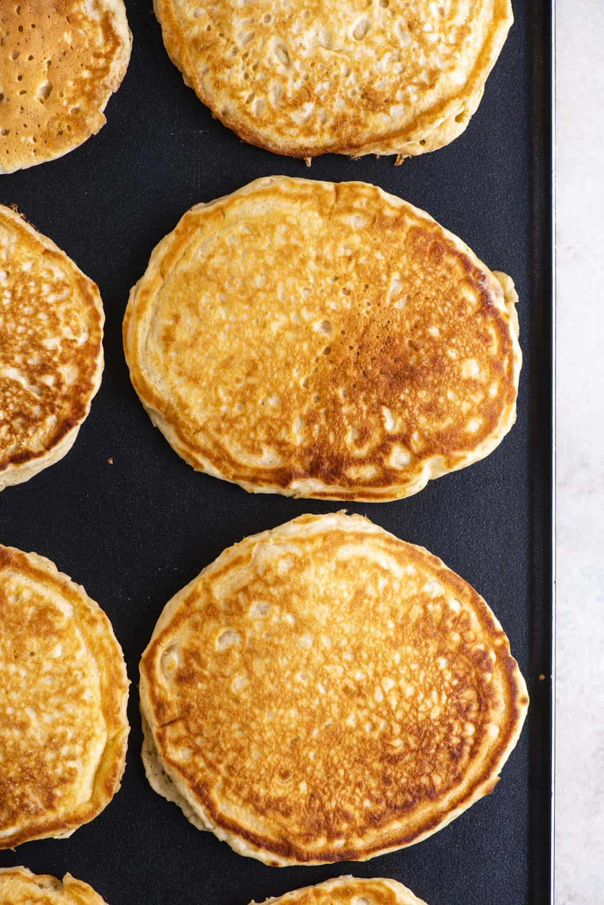 Pancakes Soffici Fatti in Casa 13 File di pancake dorati in cottura su una piastra.