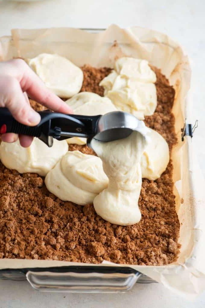 Ricetta Torta Umida al Caffè 13 Impasto di torta al caffè versato in una teglia con carta forno con una paletta da gelato sopra il topping di crumble