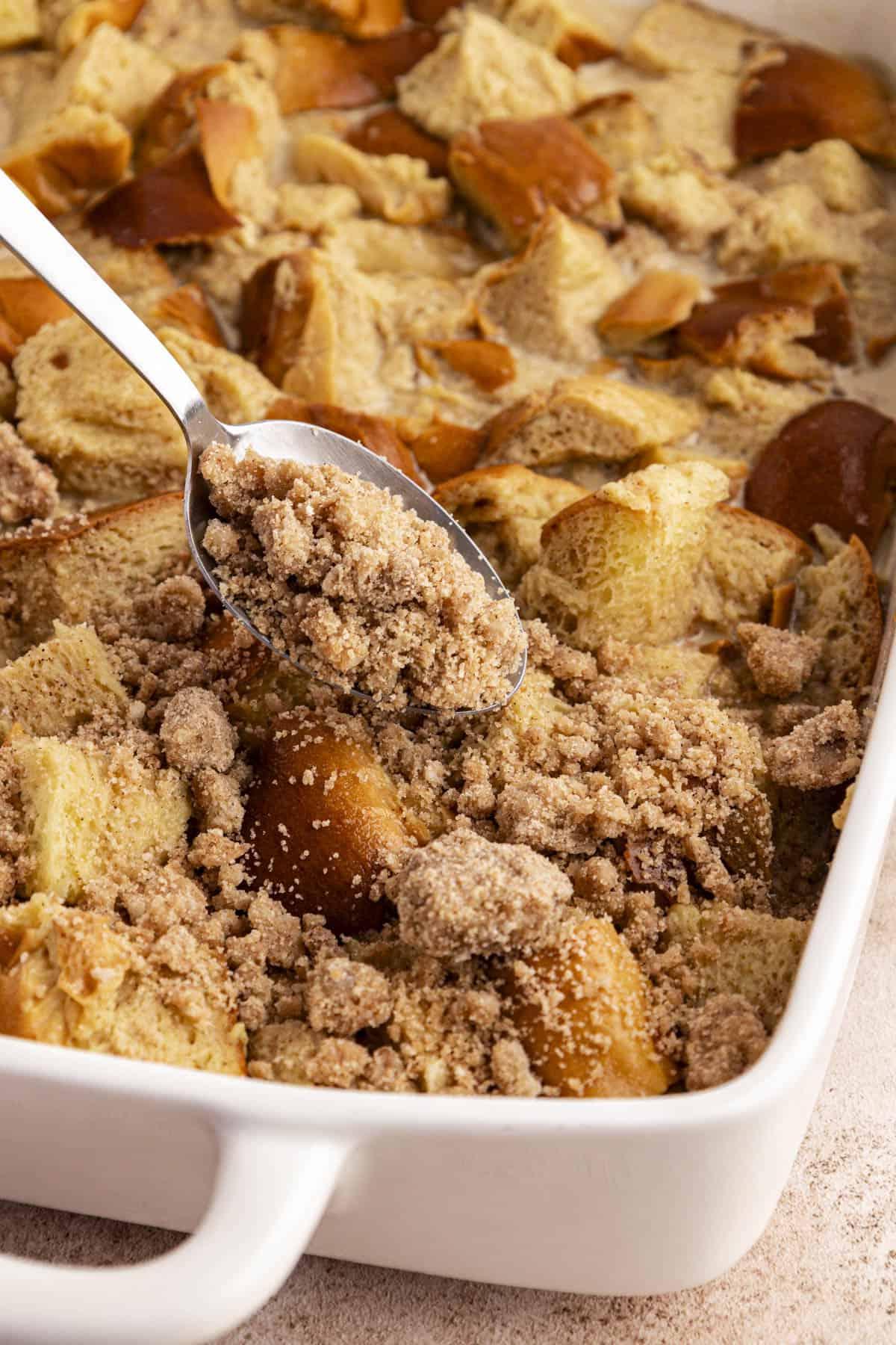 Migliore Ricetta per Budino di French Toast 13 Una teglia bianca con la miscela di French Toast con un cucchiaio di topping croccante spolverato sopra.