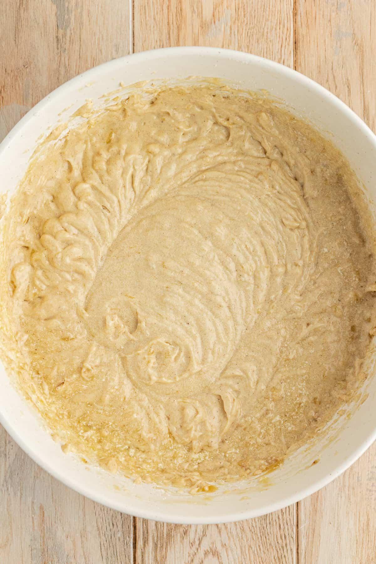 Ricetta Facile Torta alla Banana 13 Una ciotola bianca su una superficie di legno piena di impasto di torta di banane