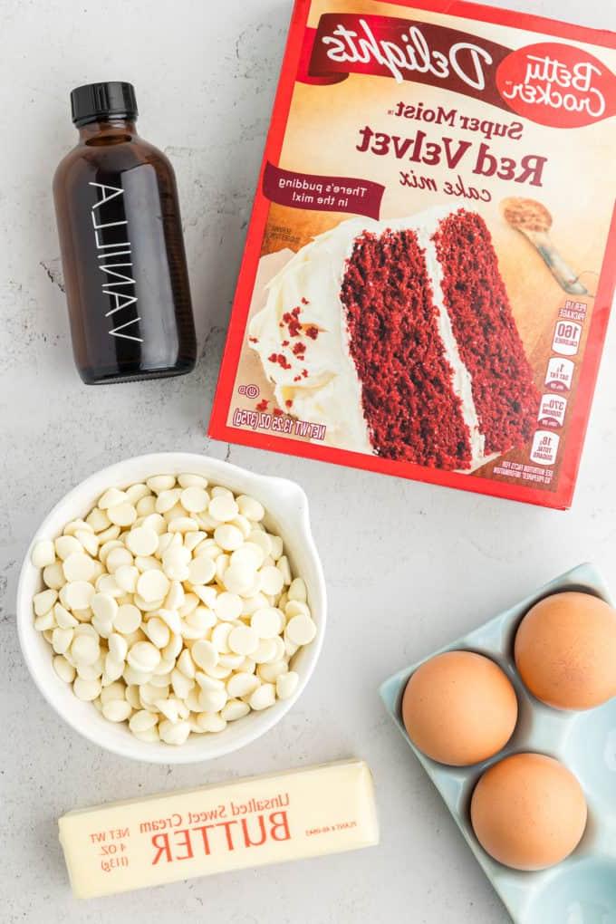 Barrette di biscotti da preparato per torte 14 a box of red velvet cake mix, a bottle of vanilla extract, a bowl of white chocolate chips, a crate of eggs, and a stick of butter