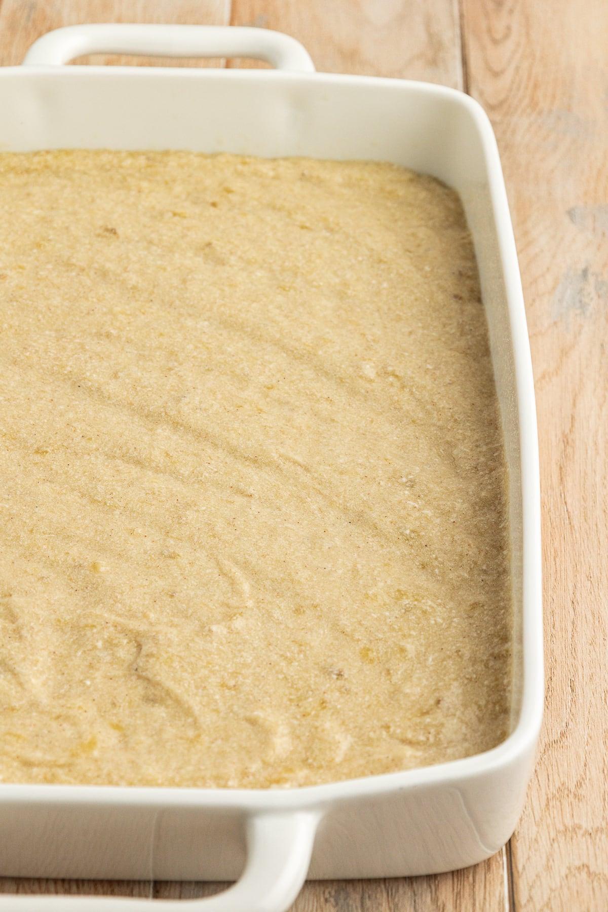 Ricetta Facile Torta alla Banana 14 Impasto di torta di banane in una teglia bianca da 9x13 su una superficie di legno