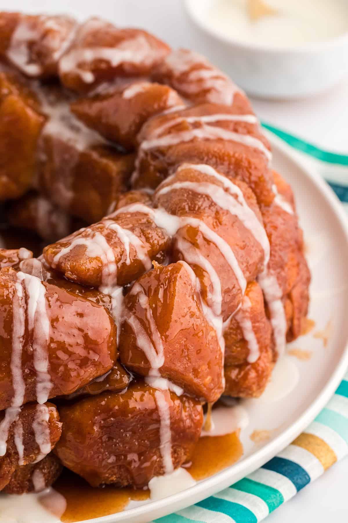 Pane delle scimmie di biscotti 14 Monkey Bread su un piatto bianco su un telo da cucina a strisce oro, turchese e blu