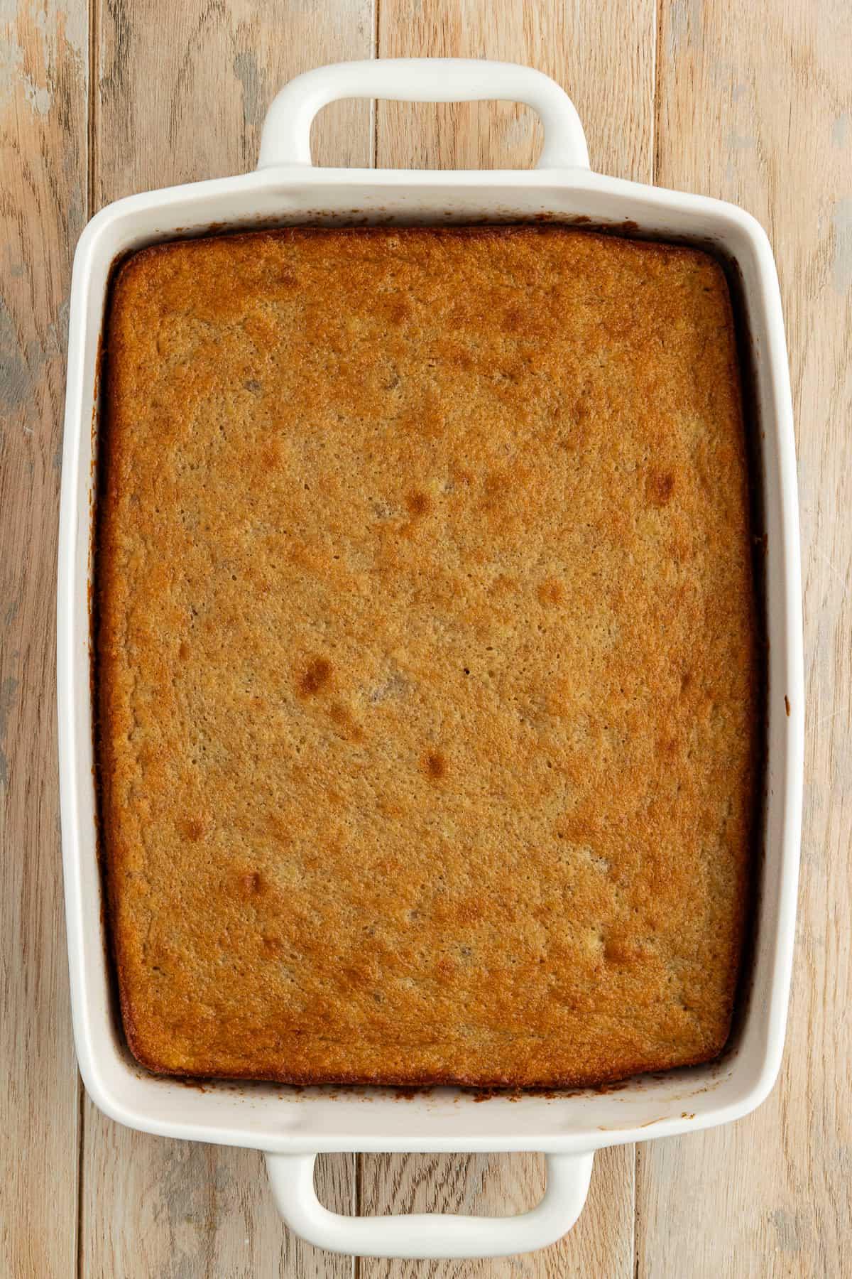 Ricetta Facile Torta alla Banana 15 Torta di banane appena sfornata in una teglia bianca da 9x13 su una superficie di legno