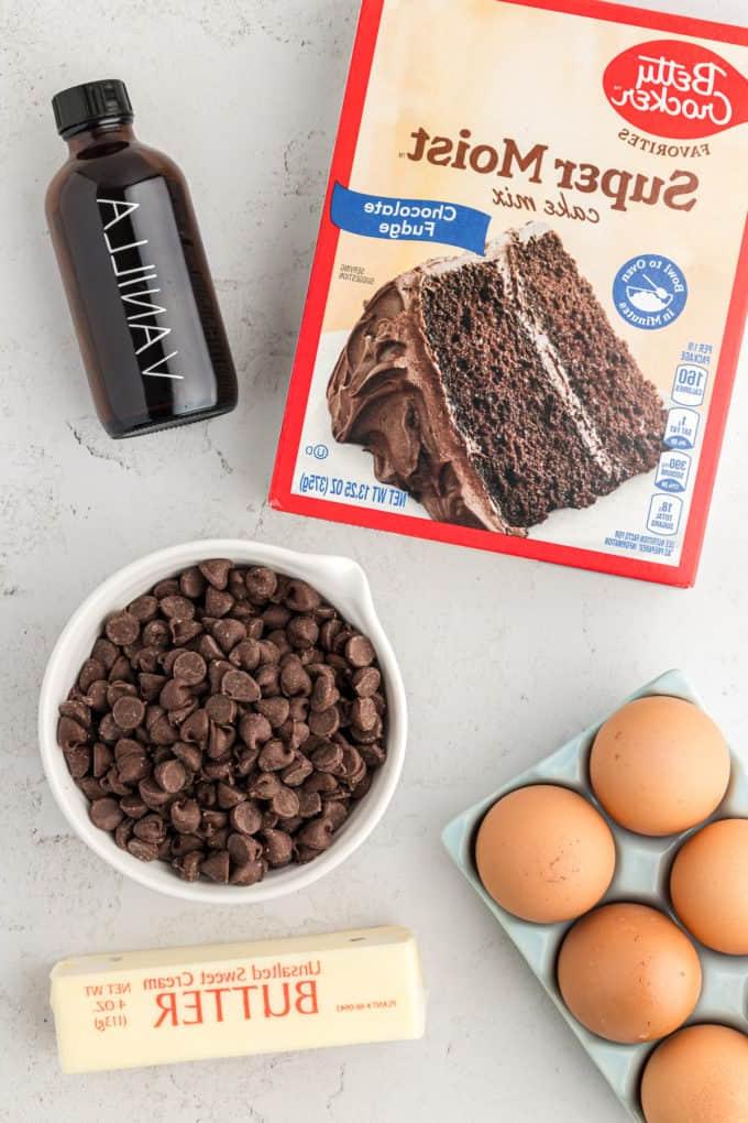 Barrette di biscotti da preparato per torte 15 a box of chocolate cake mix, a bottle of vanilla extract, a bowl of chocolate chips, a crate of eggs, and a stick of butter