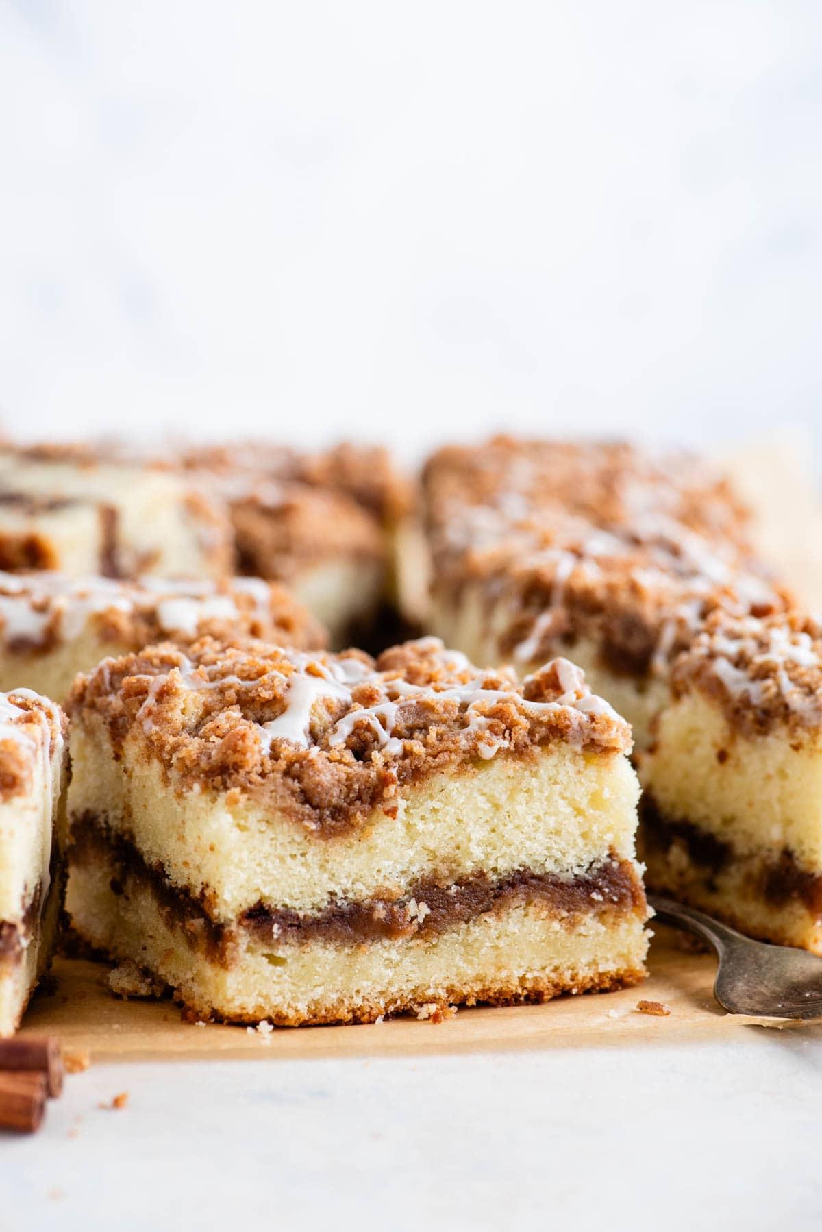 Ricetta Torta Umida al Caffè 17 Fette quadrate di torta al caffè con una forchetta e un bastoncino di cannella