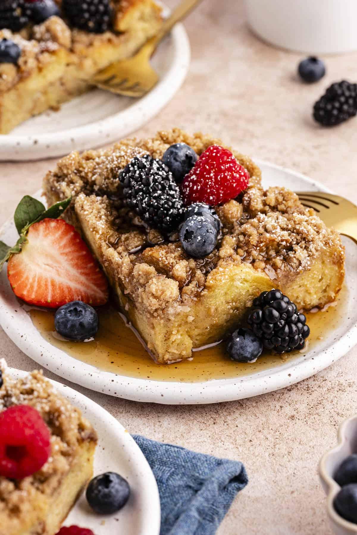 Migliore Ricetta per Budino di French Toast 17 Tre piattini con fette di casseruola di French Toast guarnite con sciroppo d'acero, frutti di bosco freschi e una leggera spolverata di zucchero a velo.