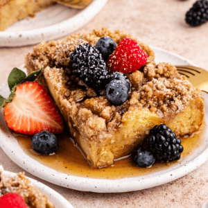 Migliore Ricetta per Budino di French Toast 18 Una fetta di casseruola di French Toast su un piattino con sciroppo d'acero e frutti di bosco freschi