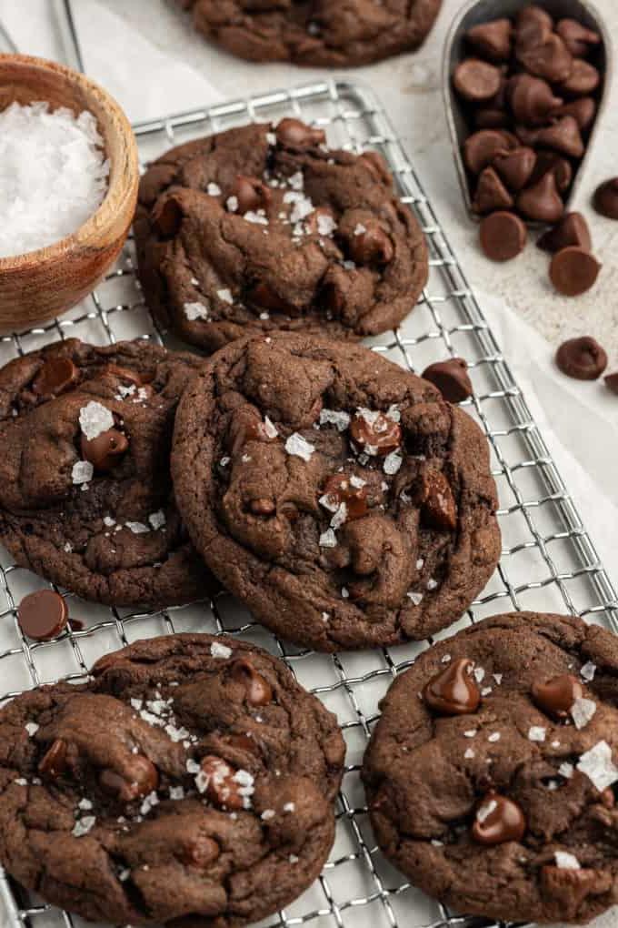 Fare Biscotti dal Mix per Torte 19 Biscotti doppio cioccolato con preparato per torte su una griglia con gocce di cioccolato sparse intorno e una piccola ciotola di legno di sale