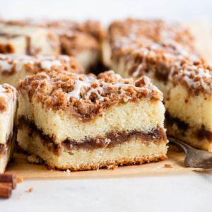 Ricetta Torta Umida al Caffè 19 Fette quadrate di torta al caffè con una forchetta e un bastoncino di cannella