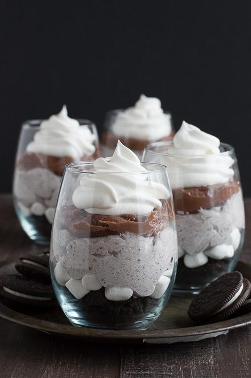 Parfait al cioccolato con strati di crema cheesecake, Oreo e panna montata in un bicchiere elegante