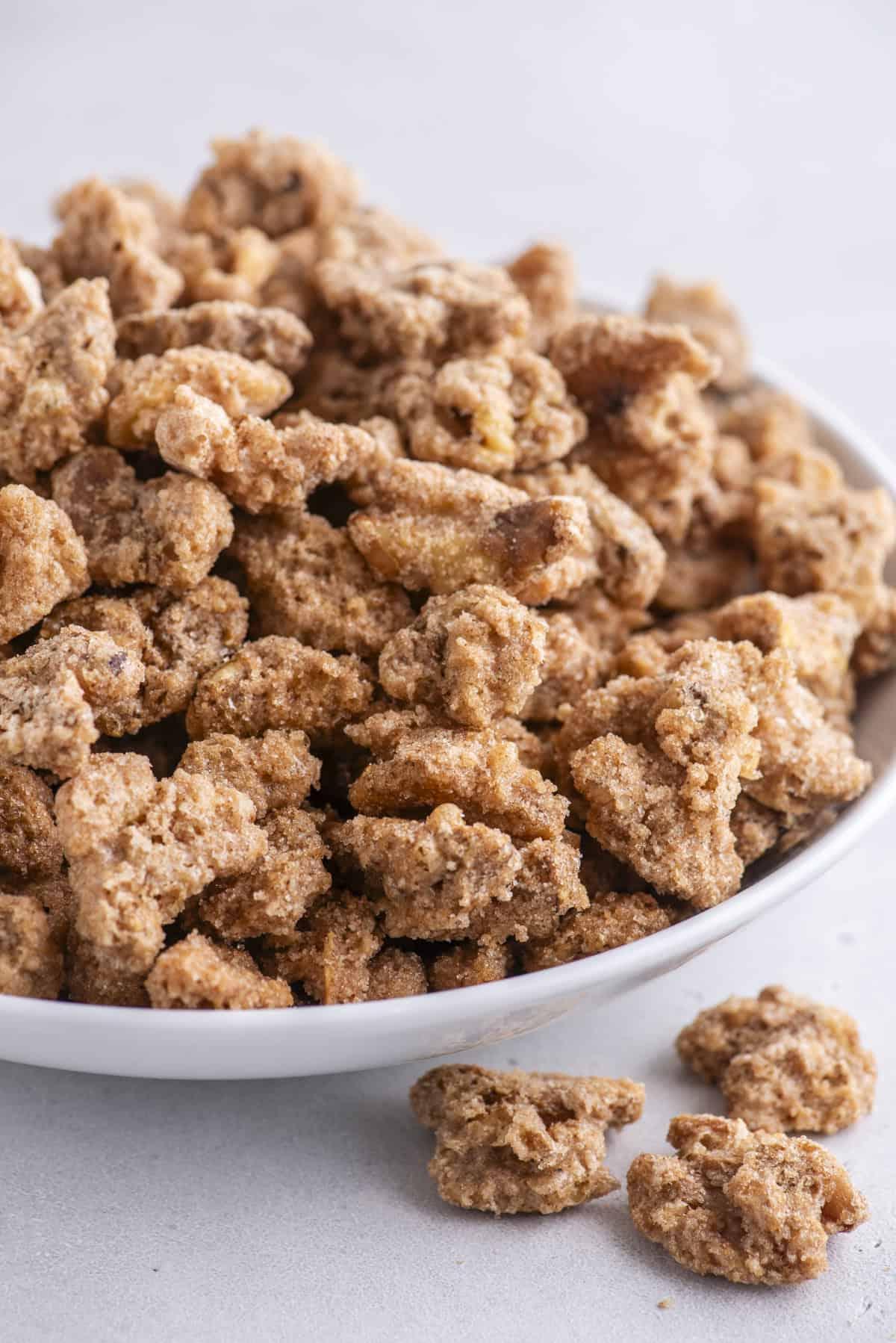 noci pralinate in una ciotola bianca, con altre tre fuori dalla ciotola