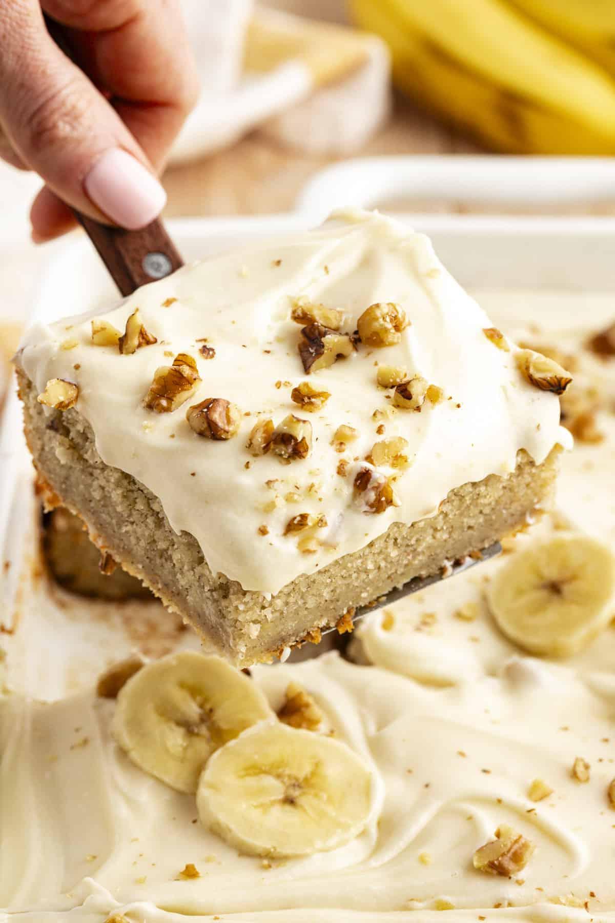 Ricetta Facile Torta alla Banana 3 Una fetta di torta di banane con noci tritate cosparse sopra, sollevata dalla teglia con una spatola
