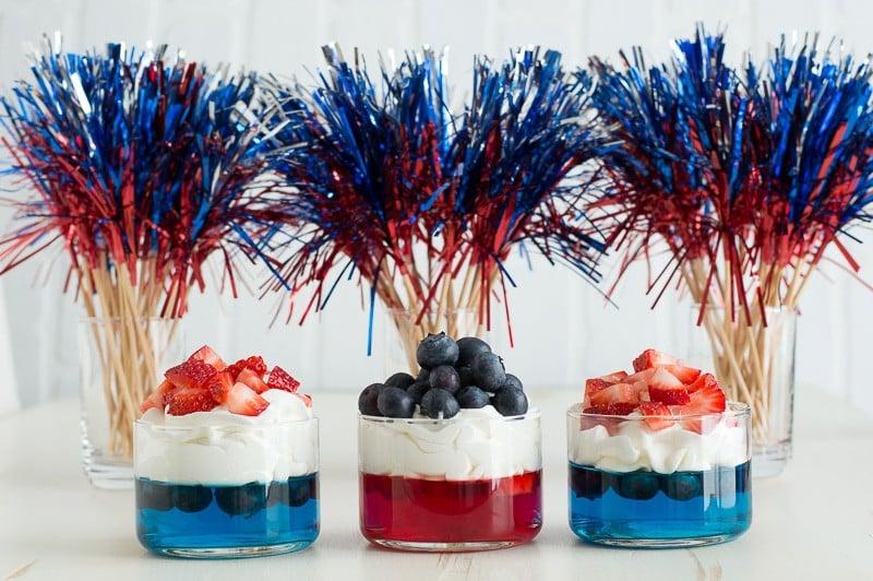 Coppette di Frutta e Gelatina per il 4 Luglio 3 Bicchierini di gelatina blu e rossa con panna montata e fragole e mirtilli tritati