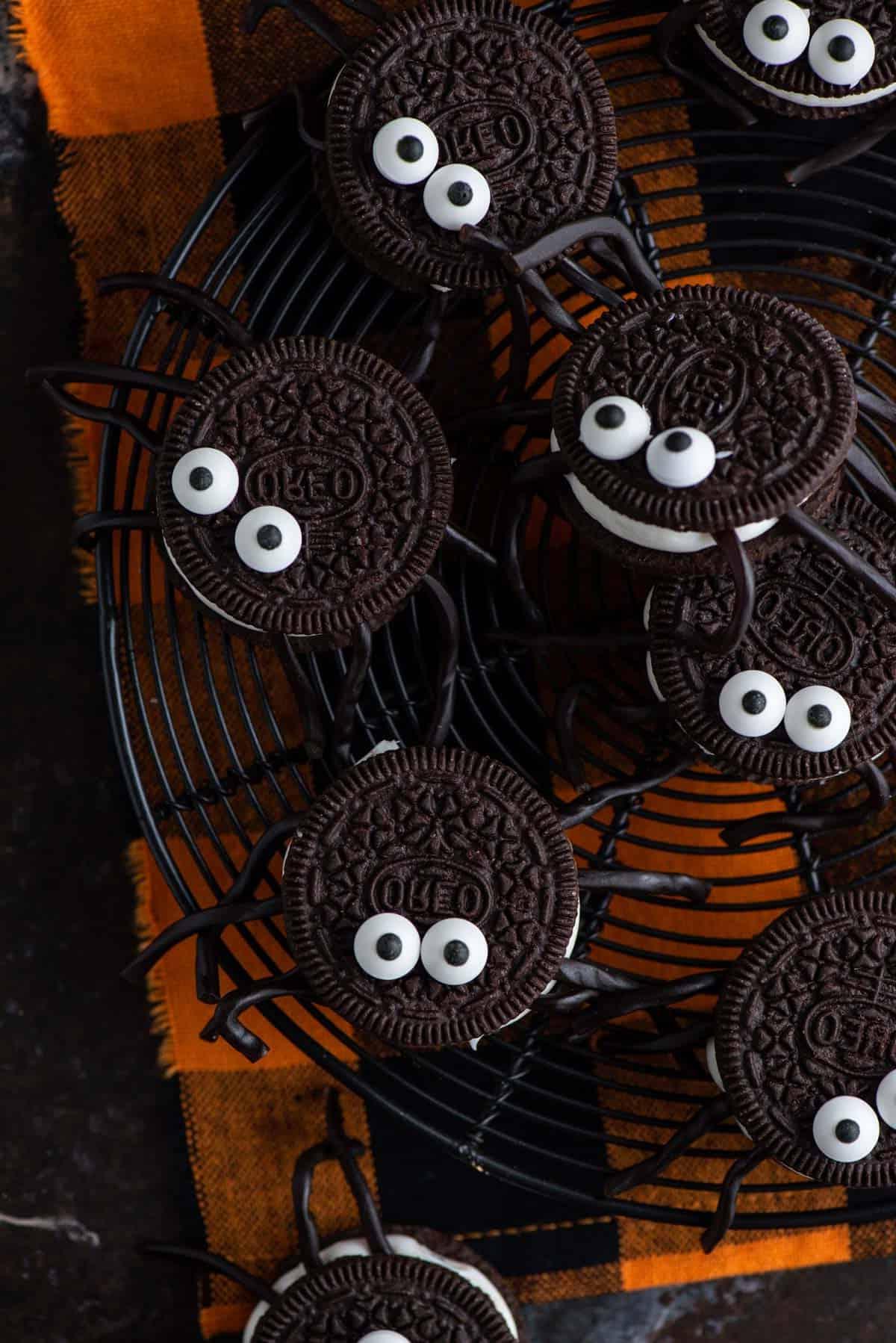 Biscotti ragno di Oreo disposti su tovaglioli arancioni a tema Halloween