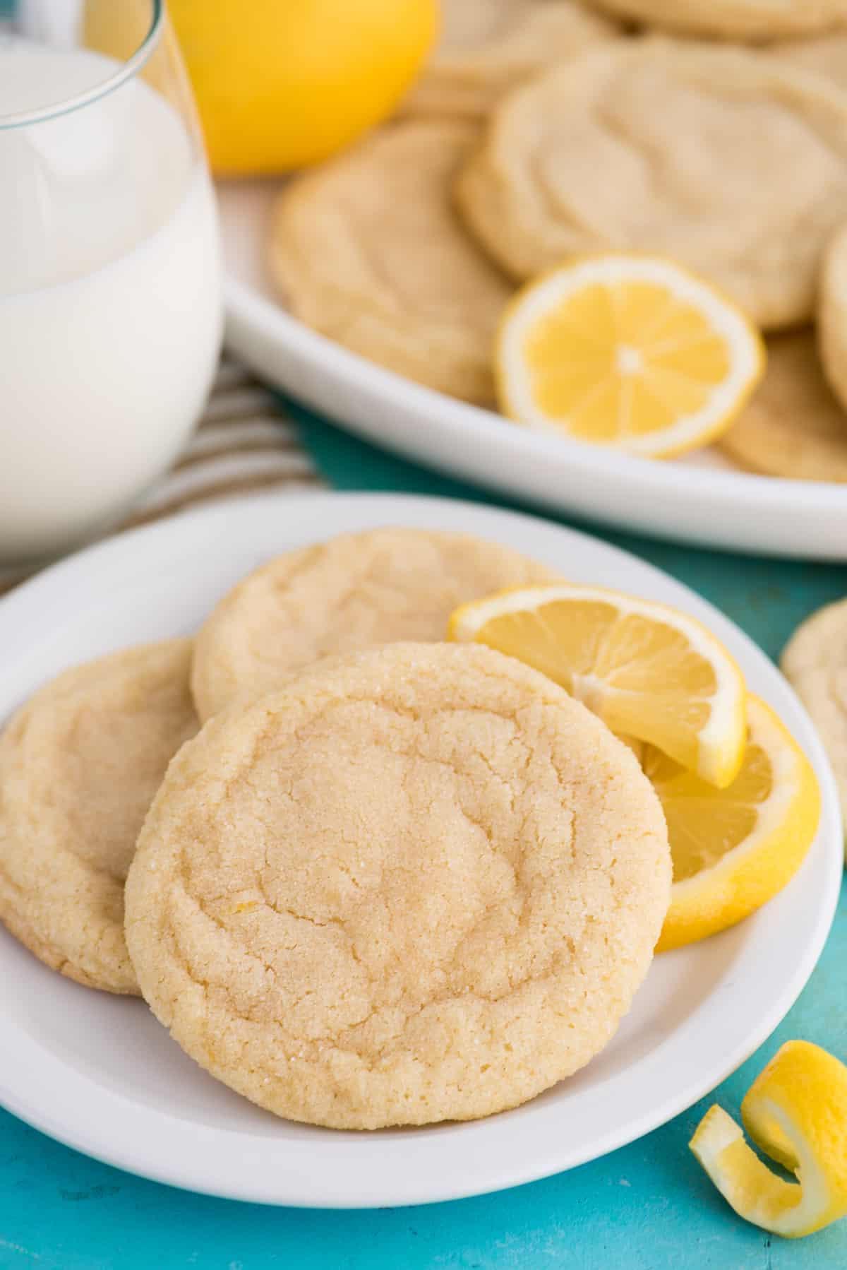 Ricetta Biscotti al Limone 3 Biscotti al limone su piatto bianco con bicchiere di latte su sfondo blu