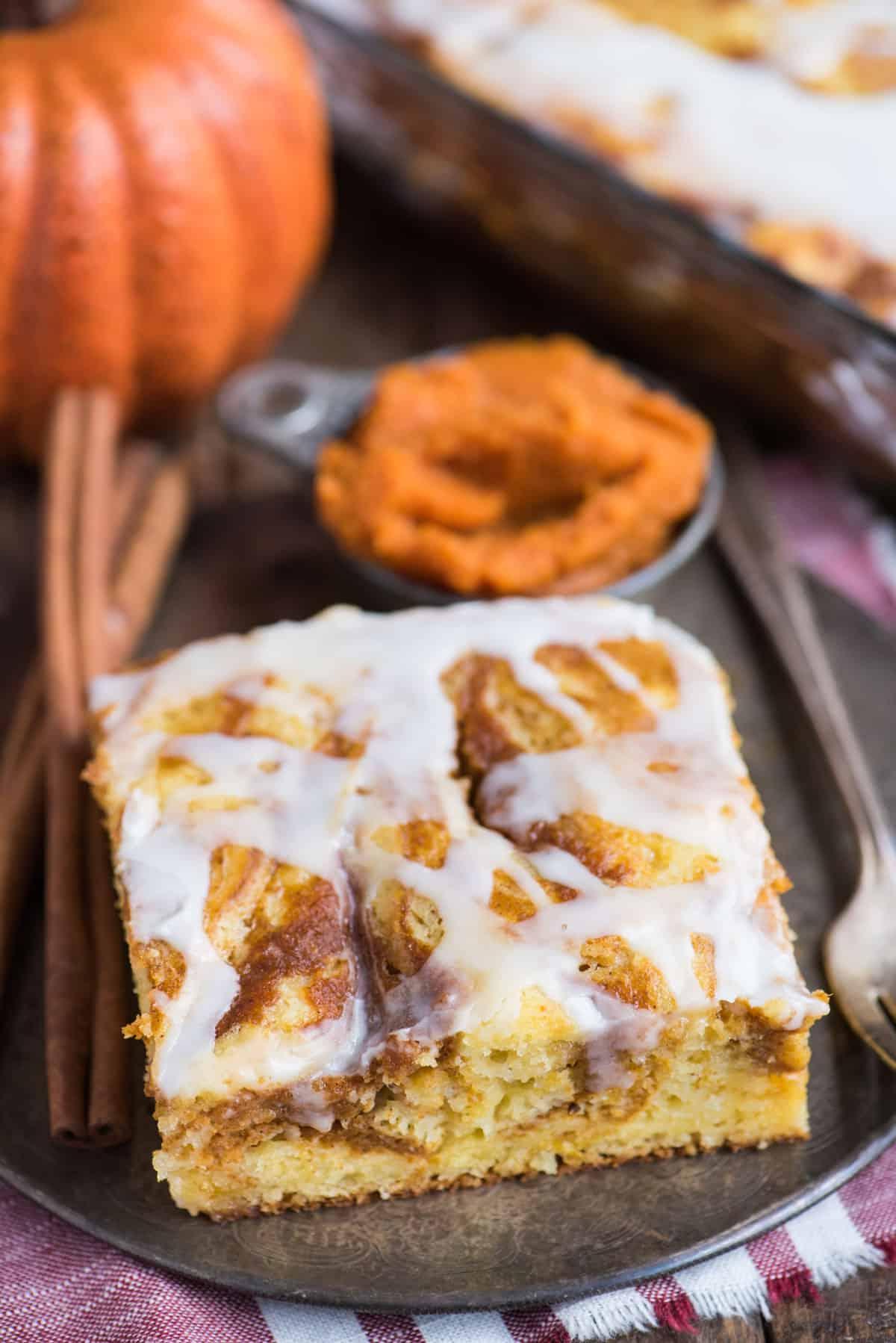 Facile Torta alla Zucca Marmorizzata 3 Fetta di torta soffice alla zucca marmorizzata con glassa bianca su un piatto di metallo.