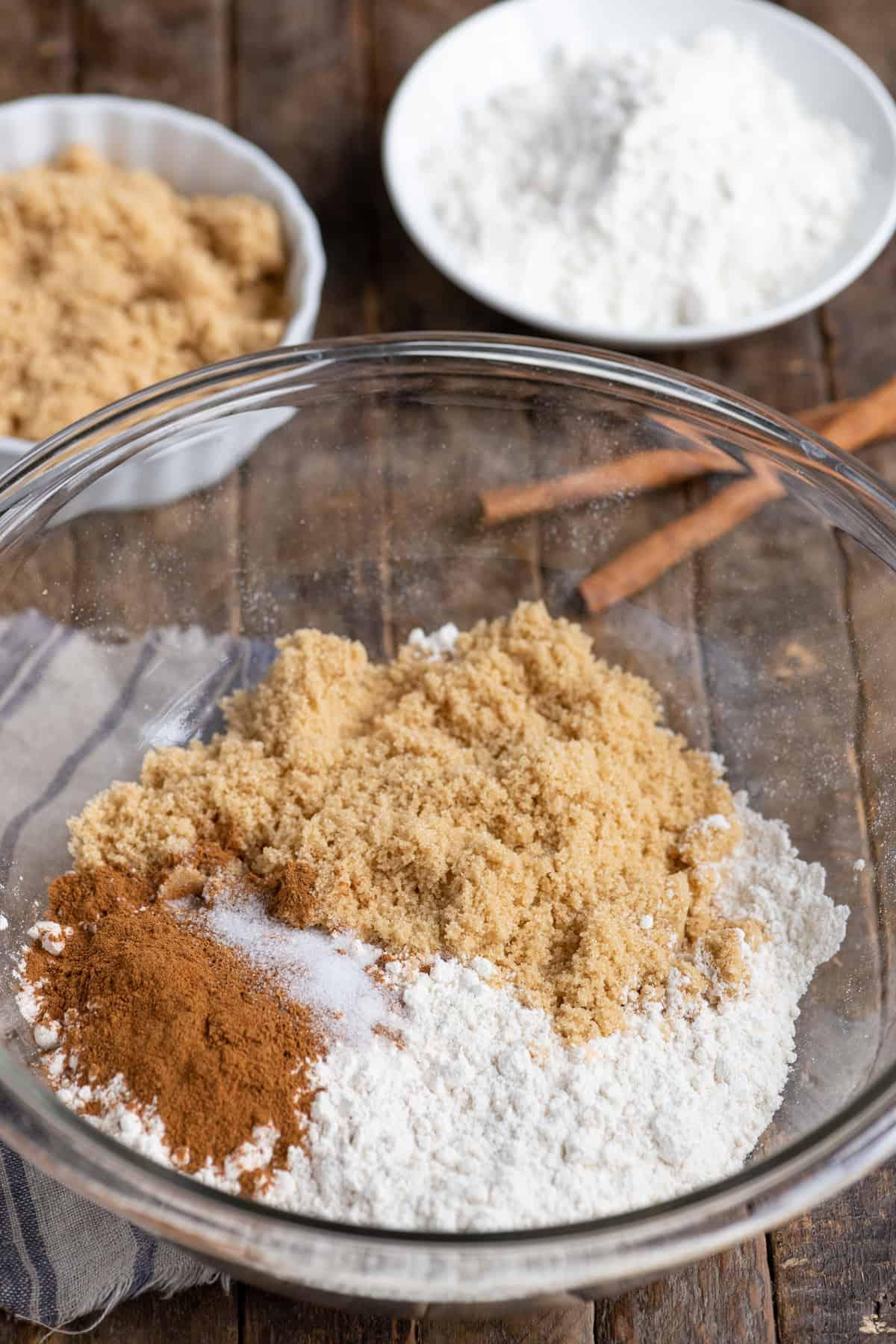 Ricetta della Copertura Sbriciolata 3 farina, zucchero di canna e cannella in ciotola di vetro su sfondo di legno