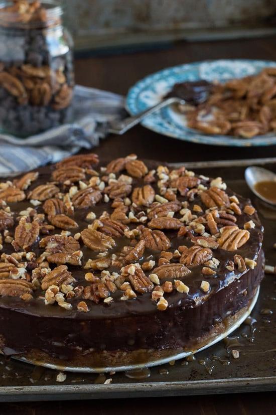 Questa è la migliore cheesecake tartaruga! È ricca e così cremosa. Guarnita con ganache al cioccolato, noci pecan e salsa al caramello.