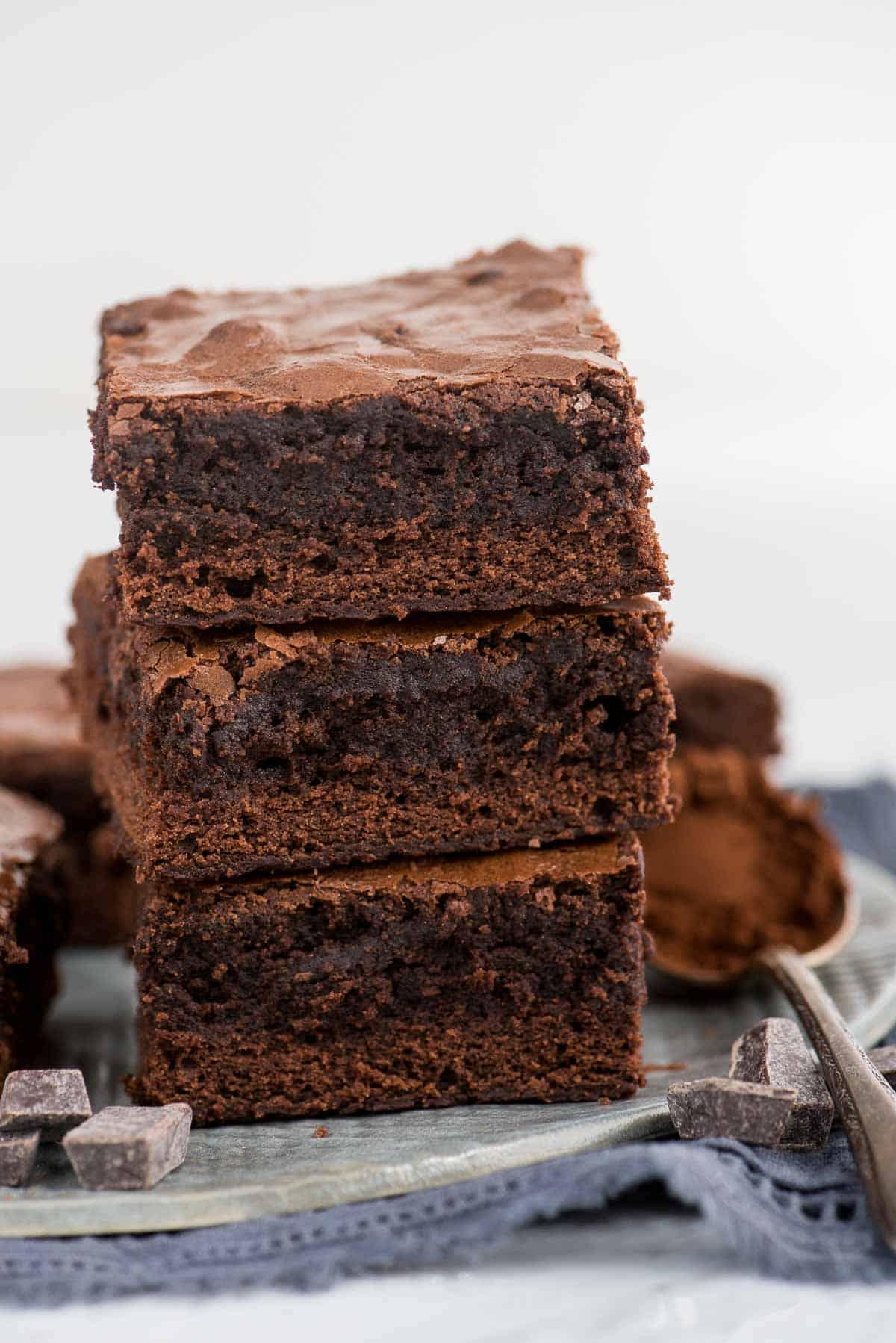 Tre brownies impilati su un piatto grigio con un tovagliolo blu