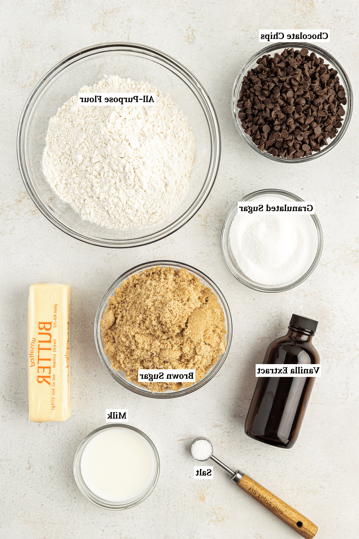 **Semplice Impasto per Biscotti Commestibile** 3 overhead view of edible cookie dough ingredients including chocolate chips, all-purpose flour, granulated sugar, brown sugar, vanilla extract, butter, milk and salt