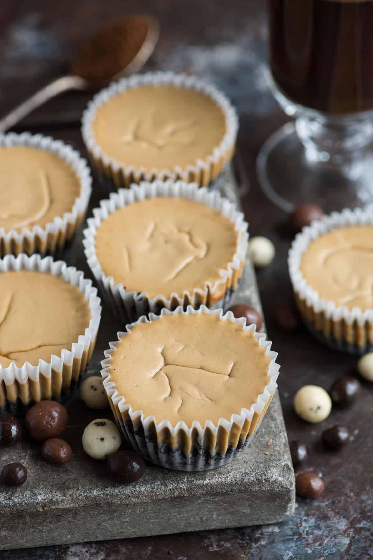 Questa è una ricetta di mini cheesecake al caffè che piacerà a tutti e che userai più e più volte! L'intera ricetta richiede solo 7 ingredienti e la prepari in uno stampo per muffin di dimensioni normali! Inoltre, puoi usare una base di Oreo o una base di cracker Graham per queste mini cheesecake all'espresso. #minicheesecake #coffeecheesecake #minicoffeecheesecake #espressocheesecake #mochacheesecake Mini cheesecake al caffè su lastra di pietra con chicchi di caffè espresso