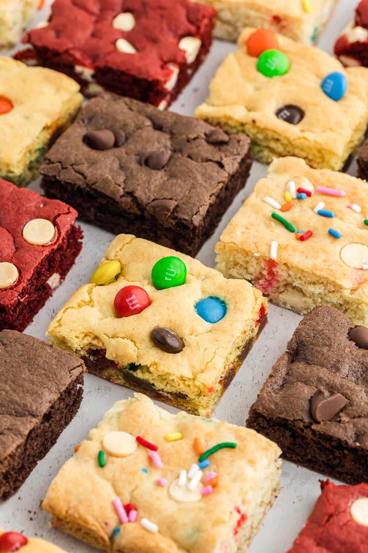 Barrette di biscotti da preparato per torte 3 rows of assorted flavors of cake bars including chocolate, red velvet, funfetti, chocolate chip, and M&M