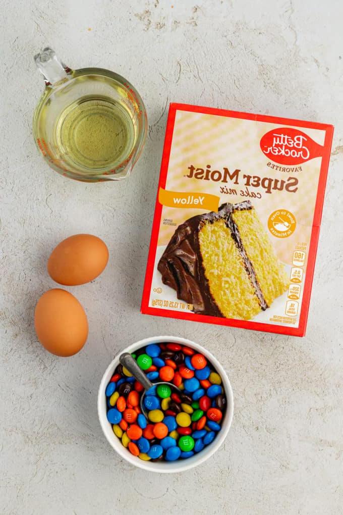 Fare Biscotti dal Mix per Torte 22 Ingredienti per biscotti M&M, inclusi olio vegetale, due uova grandi e una piccola ciotola bianca di M&M's