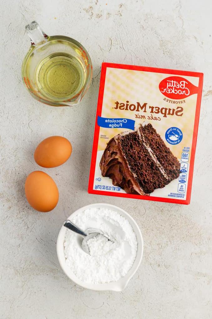 Fare Biscotti dal Mix per Torte 24 Ingredienti per biscotti Chocolate Crinkle con preparato per torte, inclusi una scatola di preparato per torte al cioccolato, olio vegetale, due uova e una piccola ciotola bianca di zucchero a velo