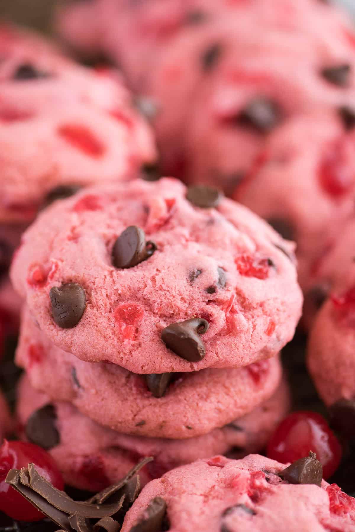 Ricetta dei Biscotti alle Amarene Maraschino 2 biscotti rosa alle ciliegie maraschino e gocce di cioccolato su teglia con ciliegie e gocce di cioccolato