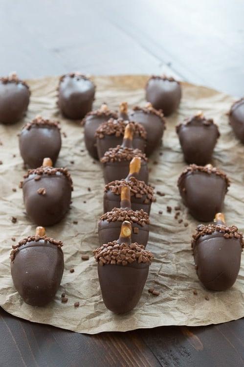 Queste palline Oreo a forma di ghianda sono COSÌ adorabili! Palline Oreo al burro d'arachidi fatte per sembrare ghiande!! Sedici dolci palline Oreo al burro d'arachidi su carta forno.