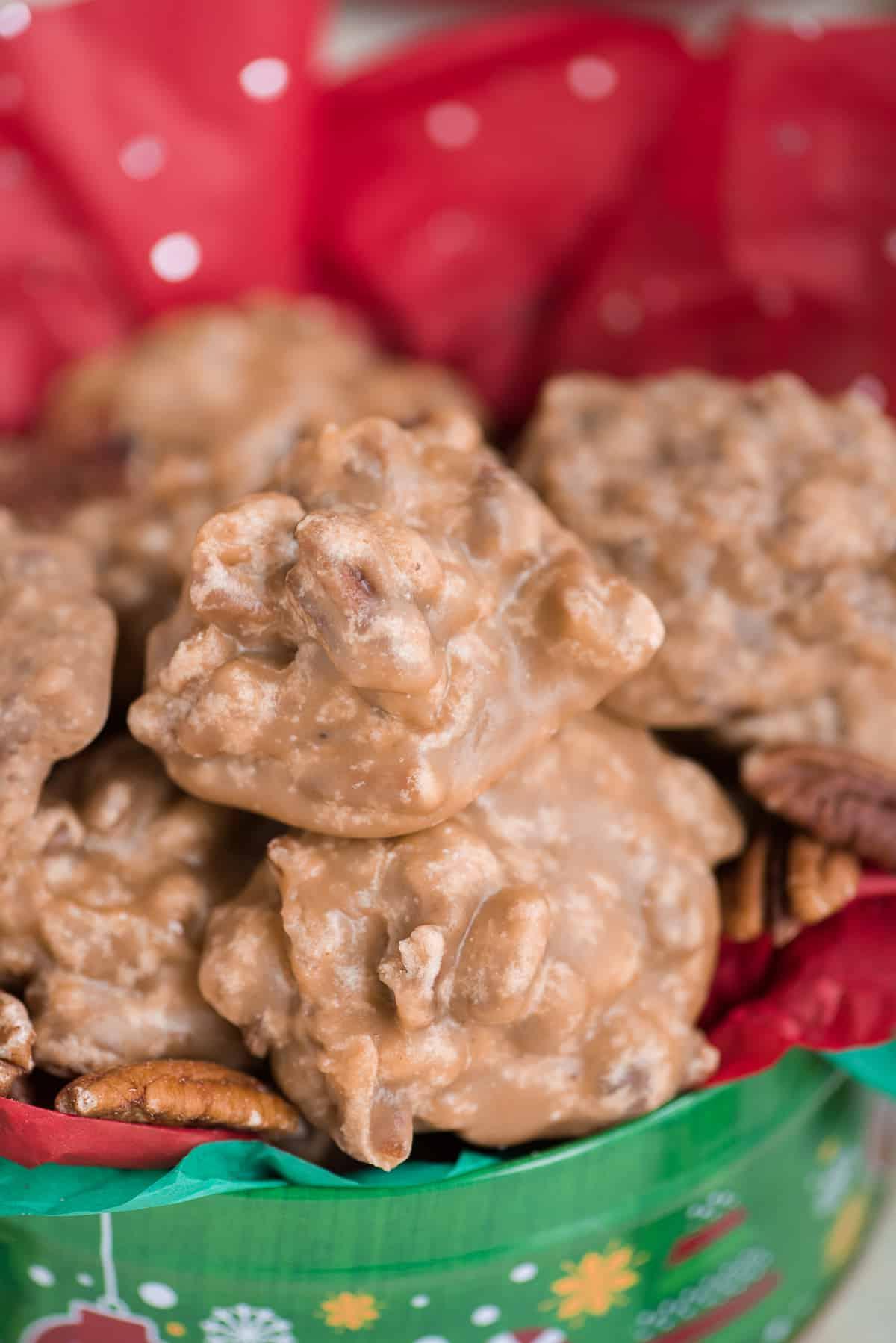 Praline al Pecan 4 Praline di pecan disposte a mucchio in una scatola natalizia con carta velina rossa