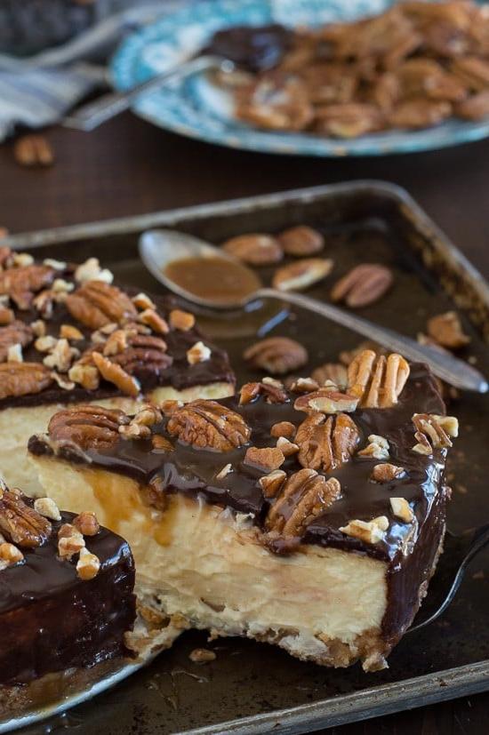 Questa è la migliore cheesecake tartaruga! È ricca e così cremosa. Guarnita con ganache al cioccolato, noci pecan e salsa al caramello.